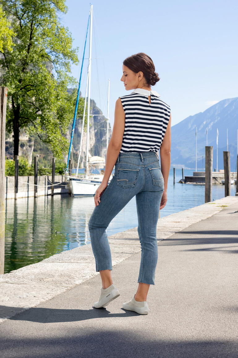 Silver Suki Straight-Jeans Frau in gestreiftem Oberteil und Jeans auf einem Gehweg am Wasser.