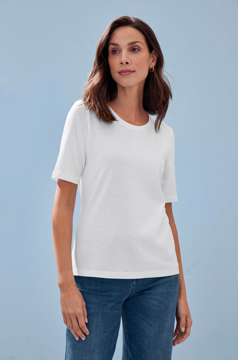 Tencel™-T-Shirt Weißes Tencel™-T-Shirt auf einem Model vor blauer Wand.