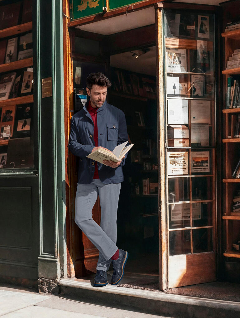 Mann in Steinbock® Ultraleicht-Cityjacke liest vor einer Buchhandlung.