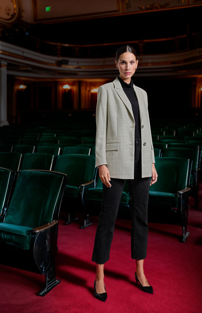 Clark Ross Baby-Alpaka-Blazer Frau in einem gerippten schwarzen Top und grauem Blazer steht in einem Theater.