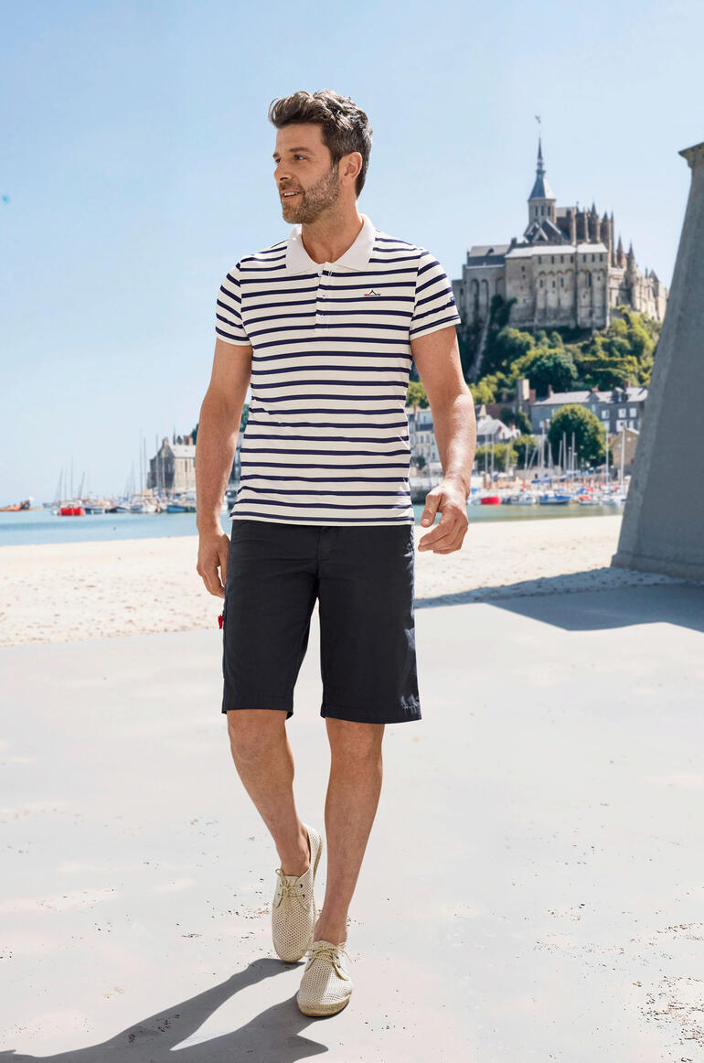 Saint James Bretagne-Poloshirt Mann in gestreiftem Saint James Bretagne-Poloshirt beim Spazieren am Strand.