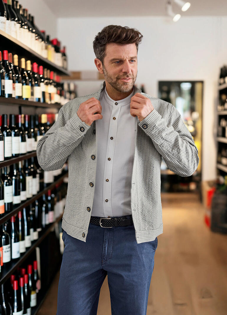 Weiß Mann zieht Leinen-Seersucker-Janker in einem Weinladen an.