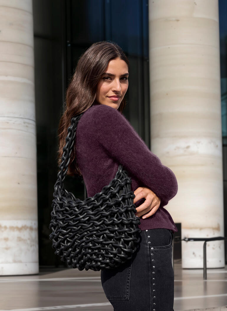 Schwarz Frau trägt braunen JH1954 Cashmere-Cardigan und hält eine schwarze Tasche