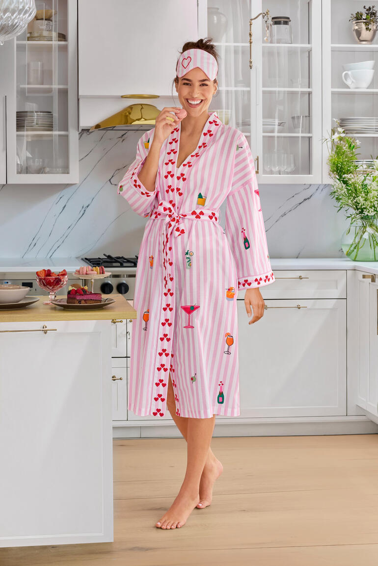 Nimo With Love Sleepover-Set Frau trägt gestreiften Morgenmantel mit bunten Motiven in einer modernen Küche.