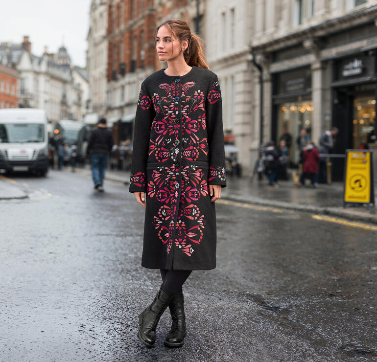 Frau trägt IVKO Wollmantel mit floralem Muster in der Stadt