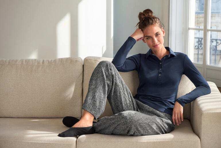 Frau trägt JH1954 Alpaka-Maritim-Pullover in offwhite auf Sofa.