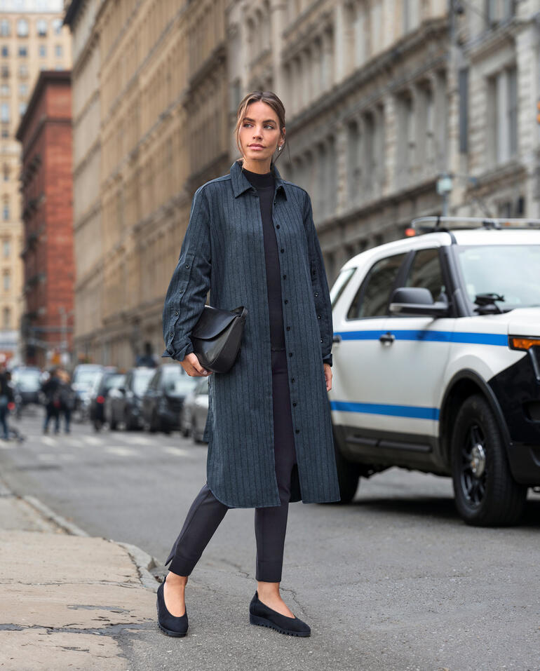 Frau in gestreiftem Longblusenkleid auf der Straße in der Stadt.