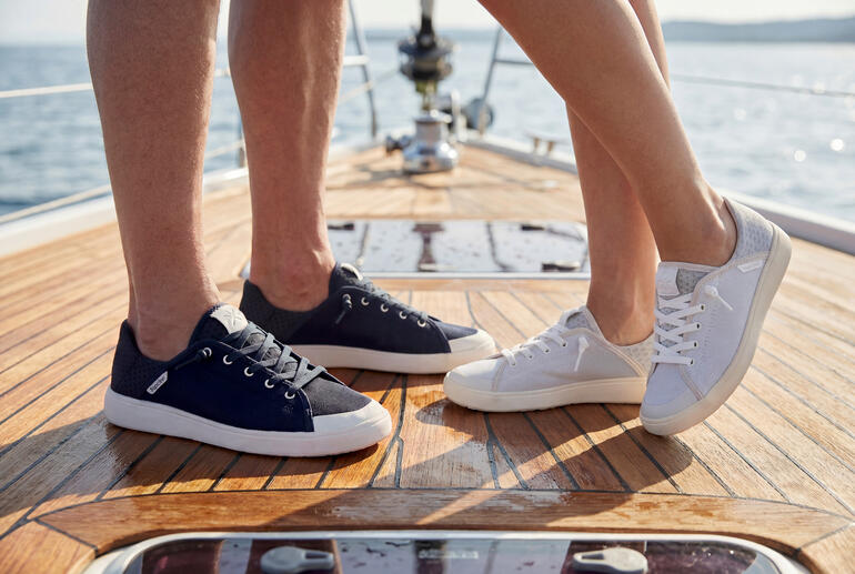 Paare in Sneakers stehen auf einem Bootsboden.