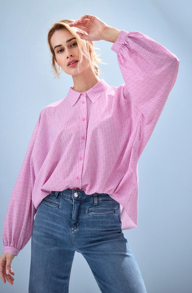 Frau in pinker gestreifter Bluse mit lockeren Ärmeln.