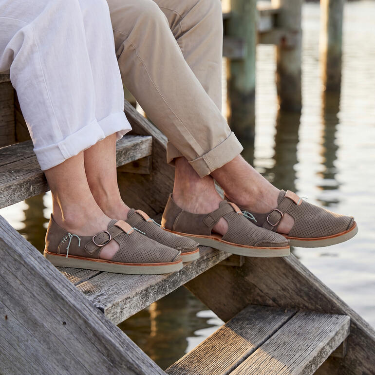 Paare in Sneaker-Sandalen entspannen auf einer Treppe am Wasser.