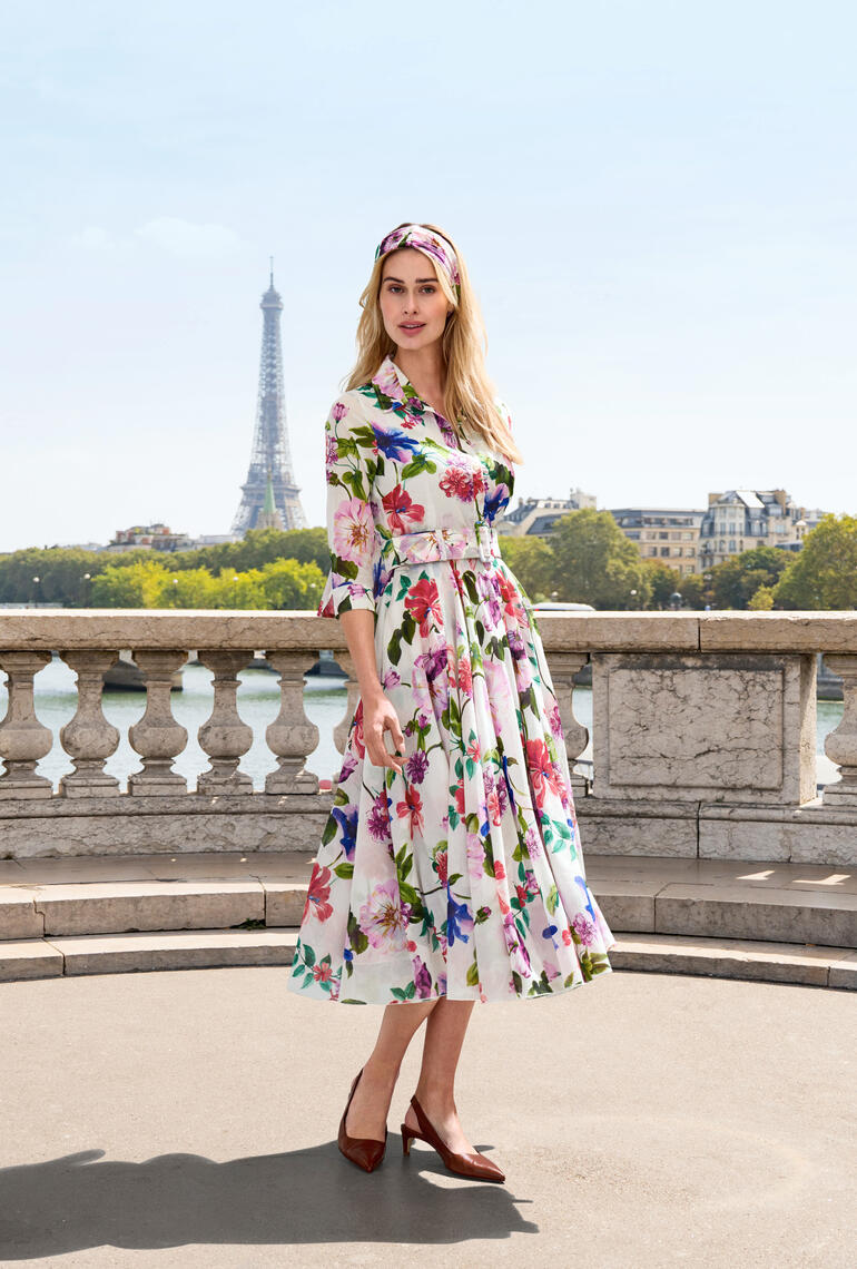 Frau trägt ein Kleid mit Hibiskusdesign, posiert vor dem Eiffelturm in Paris.
