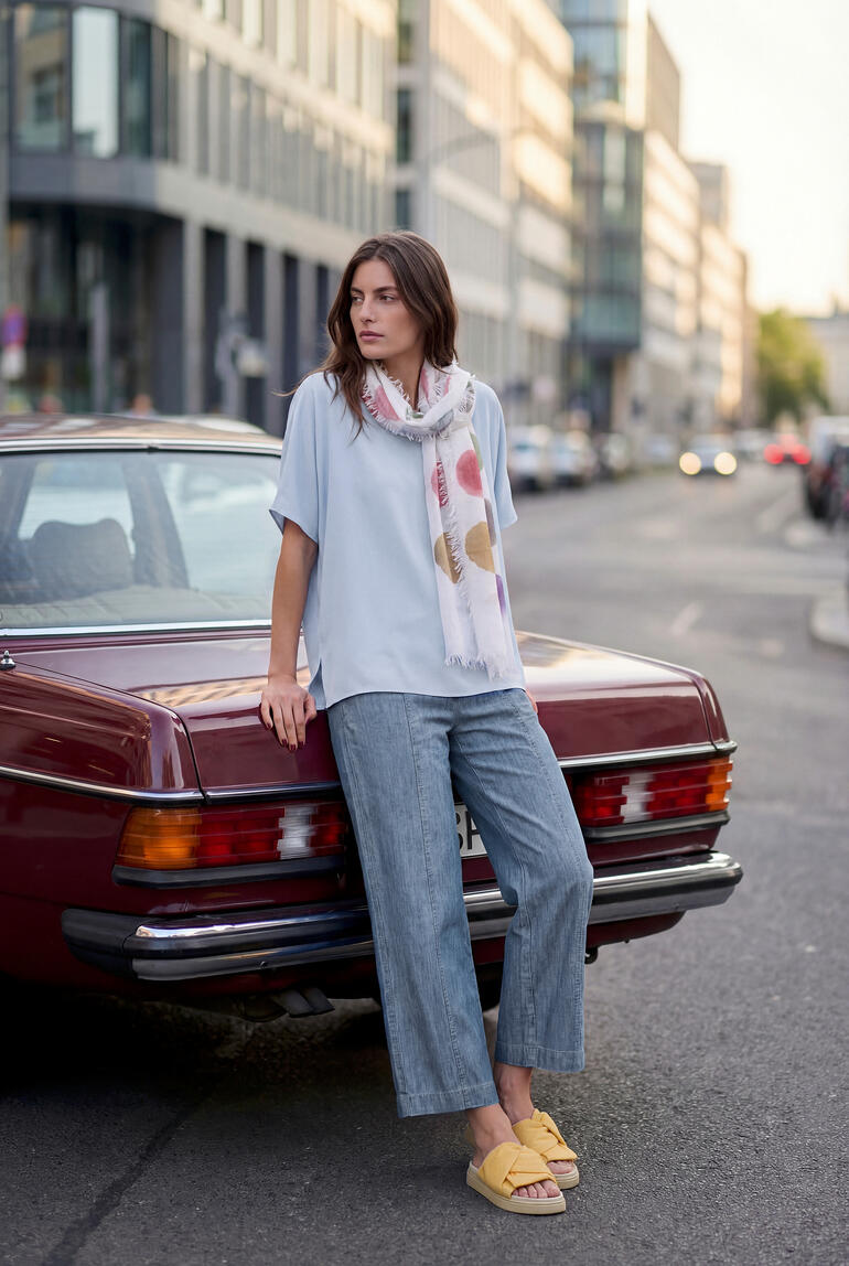 Frau in himmelblauem T-Shirt und lässigem Outfit neben Auto