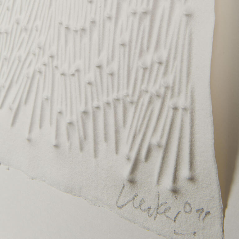 Nägel auf der Druckplatte geben dem angefeuchteten Büttenpapier das prägnante Relief. Detailaufnahme einer skulpturalen Arbeit von Günther Uecker, mit zahlreichen kleinen Erhebungen.