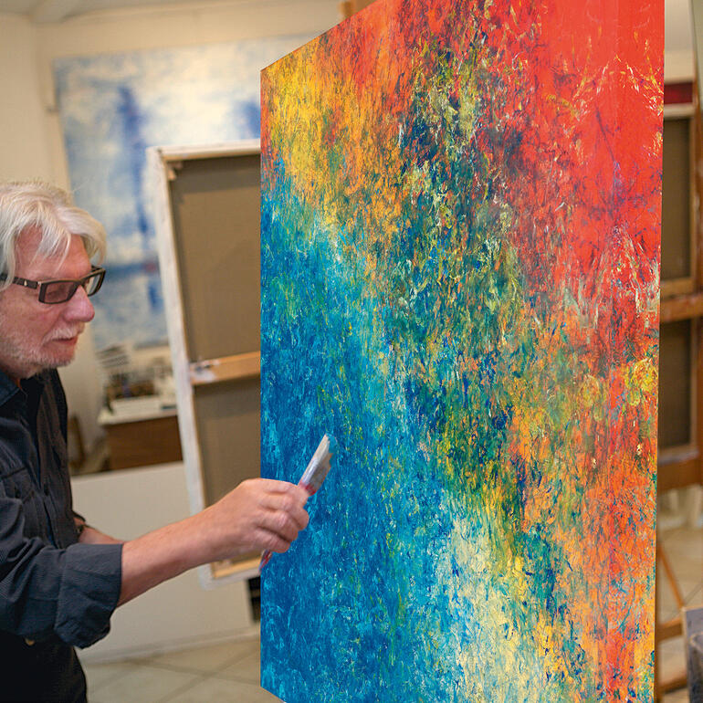 Benno Werth Künstler Benno Werth malt an einem lebhaften, abstrakten Gemälde in seinem Atelier.