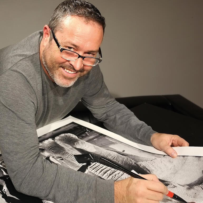 Künstler arbeitet an einem Fotodruck mit einem breiten Lächeln.