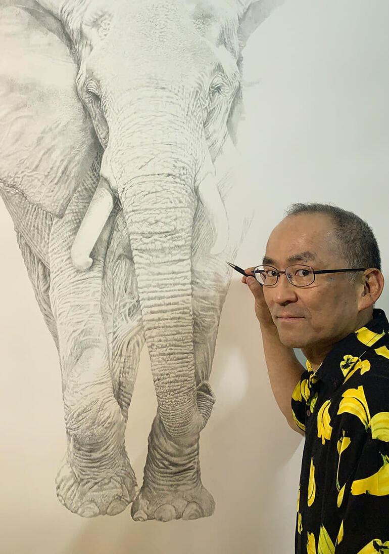 Koshi Takagi Künstler posiert neben einem großen Elefantenporträt.