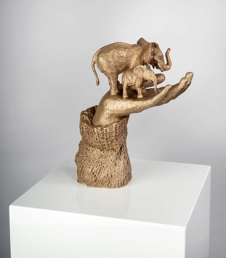 Skulptur 'Glückshand' von Marina Sailer mit drei Elefanten auf einem Hand.