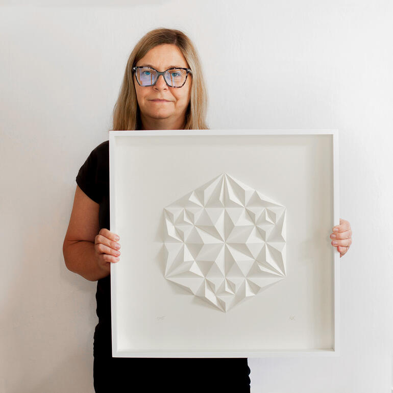 Frau hält dreidimensionale Papierkunst mit geometrischem Muster