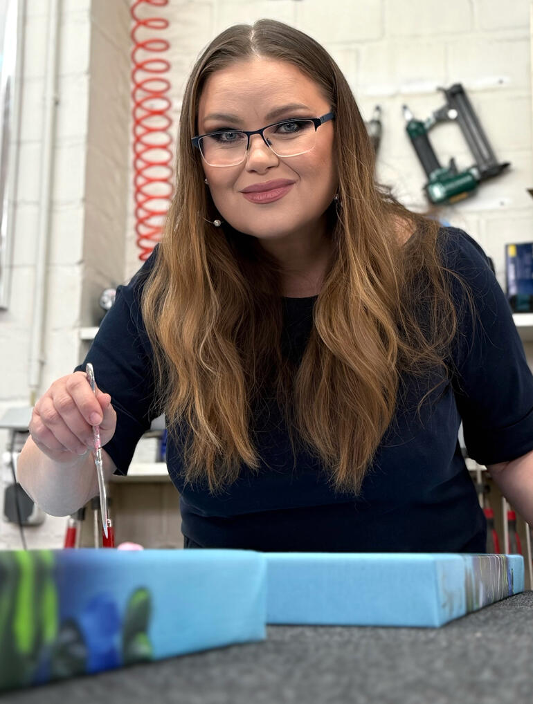 Frau mit langen Haaren, die in einem Atelier an einem Kunstprojekt arbeitet.