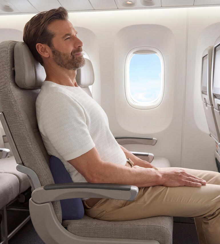 Mann sitzt im Flugzeug mit einem Reise-Rückenkissen zur Unterstützung des Rückens.