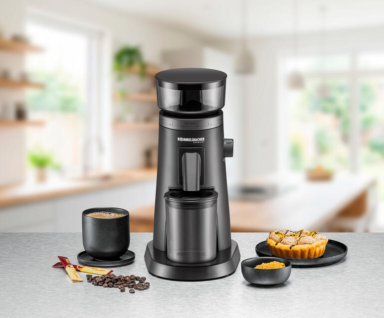 Kaffeekocher auf einer Küchentheke mit einer Tasse Kaffee und Gebäck.
