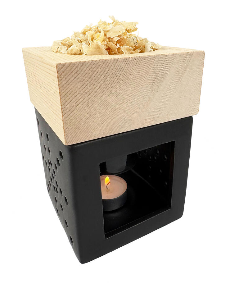 Zirbenholz-Kraftwerk mit Holzspänen auf einem Tisch, beleuchtet von einem Teelicht.