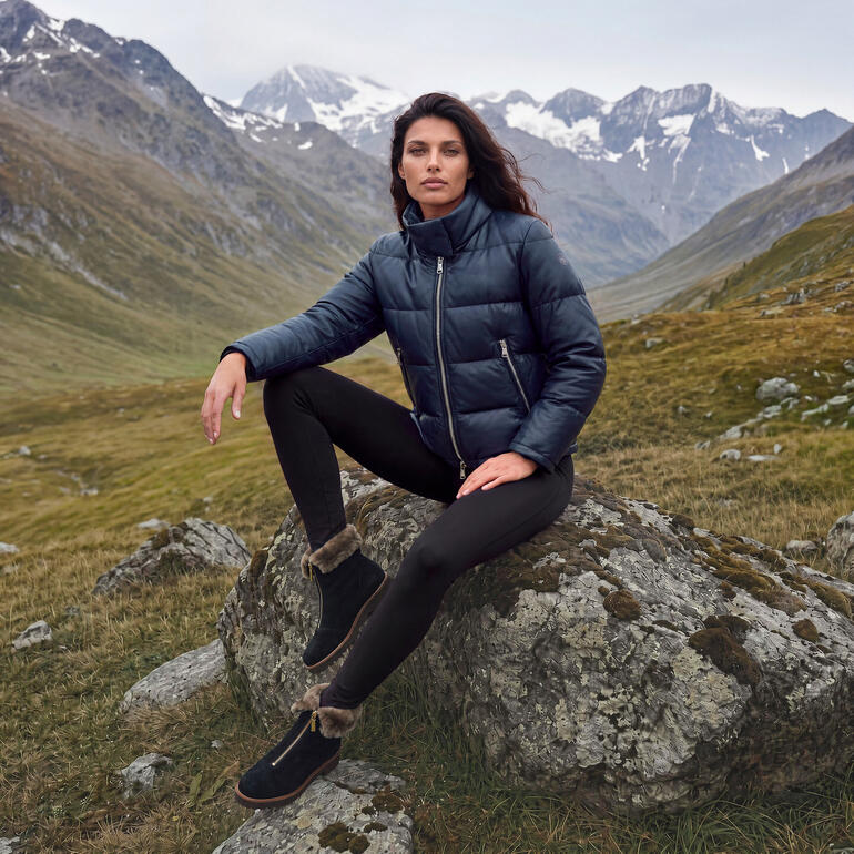 Frau mit dunkelblauer Winterjacke und schwarzen Leggings in Berglandschaft