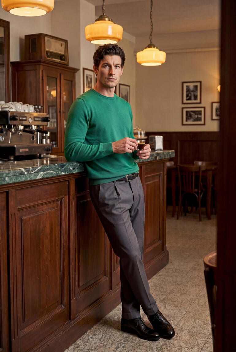 Mann in Junghans 1954 Seiden-Pullover steht an der Bar eines Cafés.