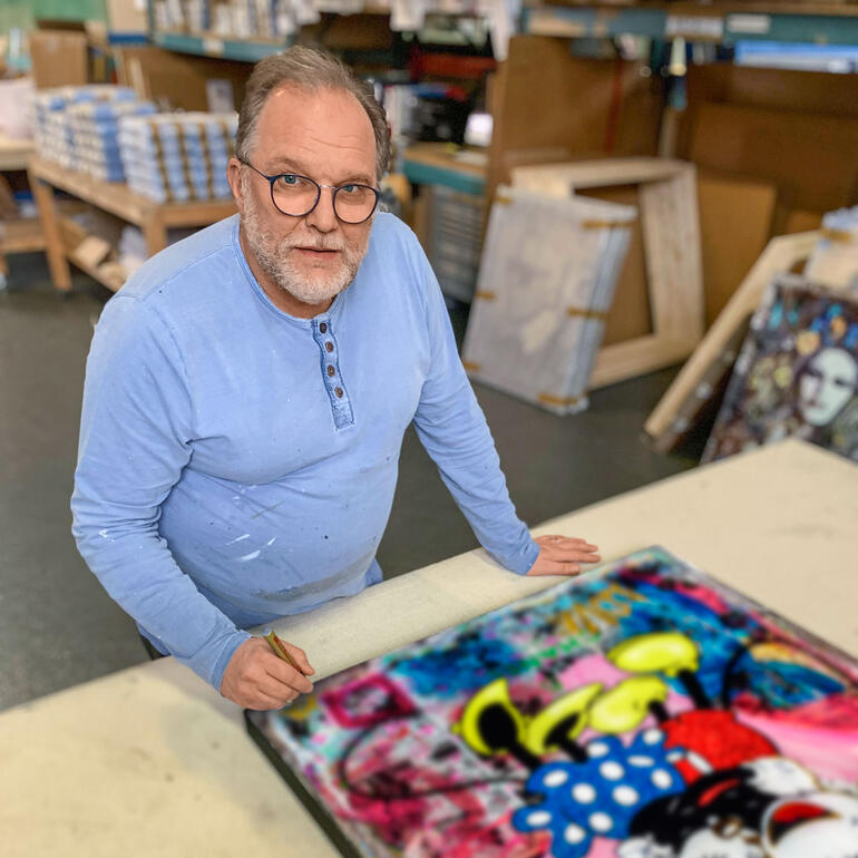 Devin Miles Devin Miles steht an einem Tisch und arbeitet an einem farbenfrohen Kunstwerk.