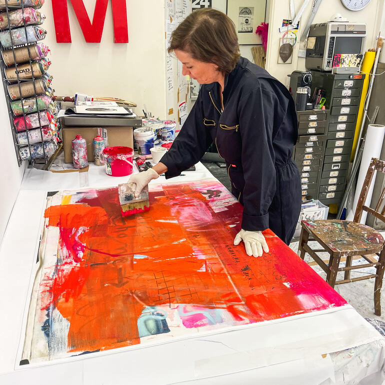 Manuela Karin Knaut Manuela Karin Knaut arbeitet konzentriert an einem Kunstwerk mit orangefarbener Farbe.