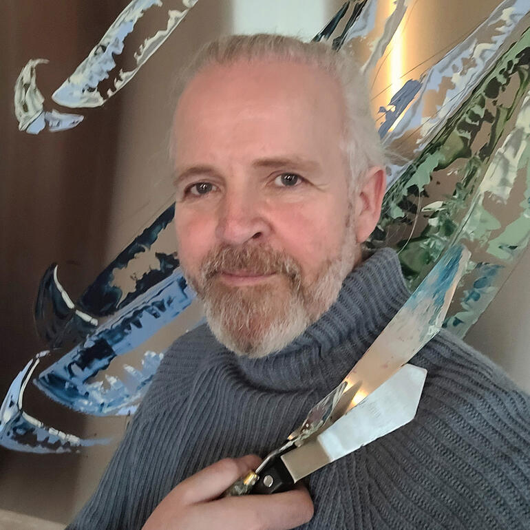 Paul La Poutré Paul La Poutré posiert mit einem Messer und einer künstlerischen Skulptur im Hintergrund.