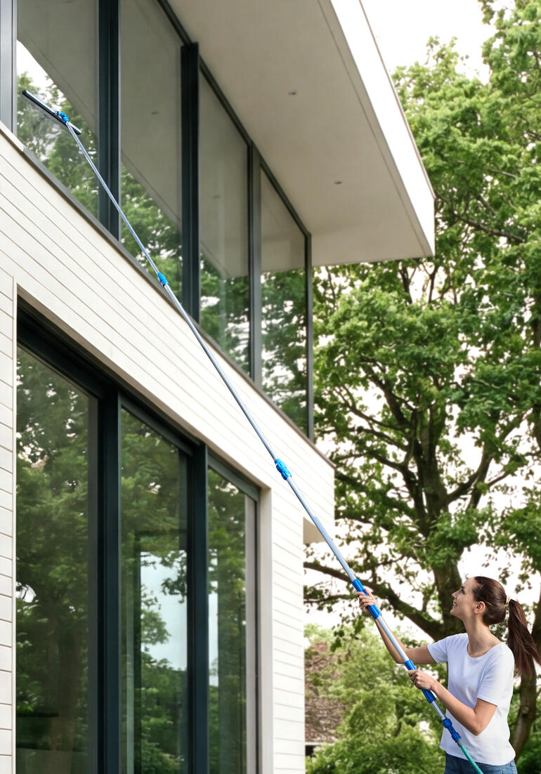 Frau reinigt Fenster mit Glas-Oberflächen-Cleaning-Set